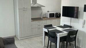 Een compacte leefruimte met een kitchenette, een eethoek en een bank.
