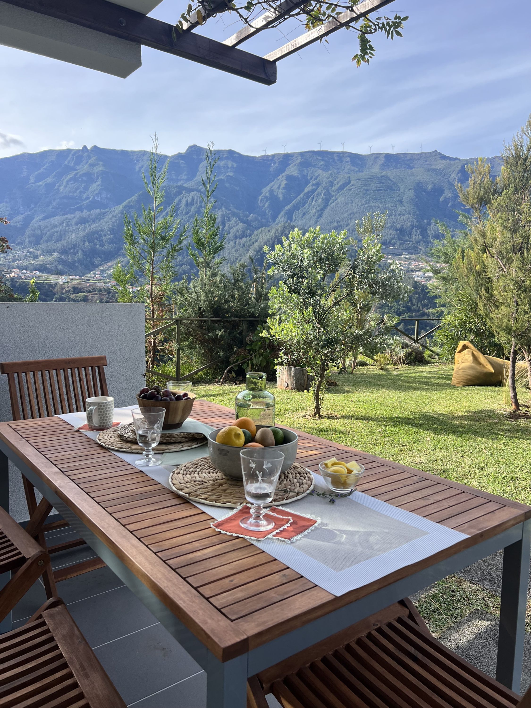 A wooden table set outdoors with a view of mountains and wind turbines in the background.