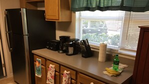 A kitchen with wooden cabinets, a stainless steel refrigerator, a coffee maker, and a window with blinds. - 3-bedroom house in marvelous Hudson with AC, WiFi (Hudson)
