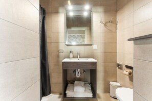 Un baño moderno con lavamanos, espejo, toallero y retrete.