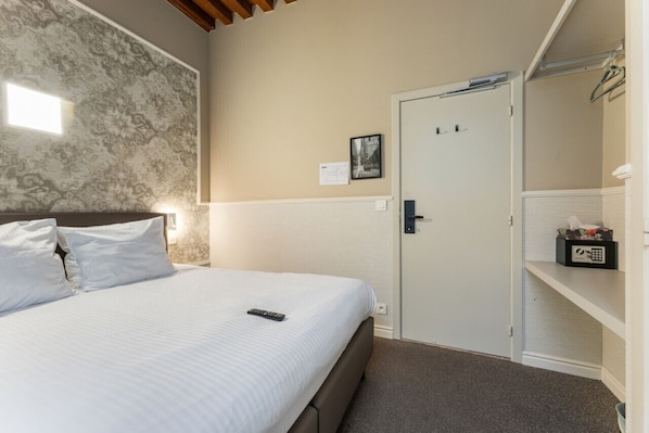 A hotel room with a large bed, a wardrobe, a door with a lock, and a small shelf with a tissue box. - Historic Double Room in Bruges Center (Brugge)