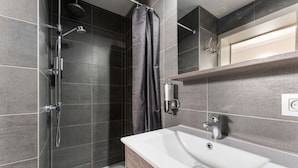 Une salle de bain moderne avec une douche, un lavabo et un miroir.