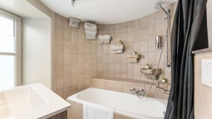 A modern bathroom with a bathtub, shower, and sink. There are stone shelves with plants and towels on the wall. - Contemporary Room in Bruges' Heart (Brugge)