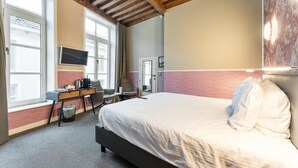 A hotel room with a bed, a desk with a chair, a television, and large windows. - Hotel Karel de Stoute (Brugge)