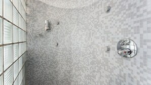 A modern bathroom with a mosaic tile floor, a glass shower enclosure, and a built-in toilet. - Hotel Karel de Stoute (Brugge)