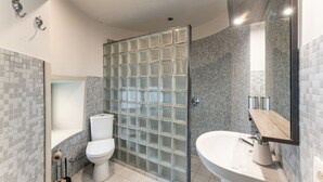 A modern bathroom with a glass shower enclosure, a white toilet, and a sink with a wooden countertop. - Hotel Karel de Stoute (Brugge)