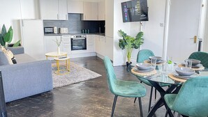 Eine moderne Küche mit weißen Schränken, einem eingebauten Backofen und einem an der Wand befestigten Flachbildfernseher.