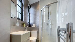 Ein modernes Badezimmer mit einer gläsernen Duschkabine, einem Waschtisch mit Spiegel und einer Toilette.
