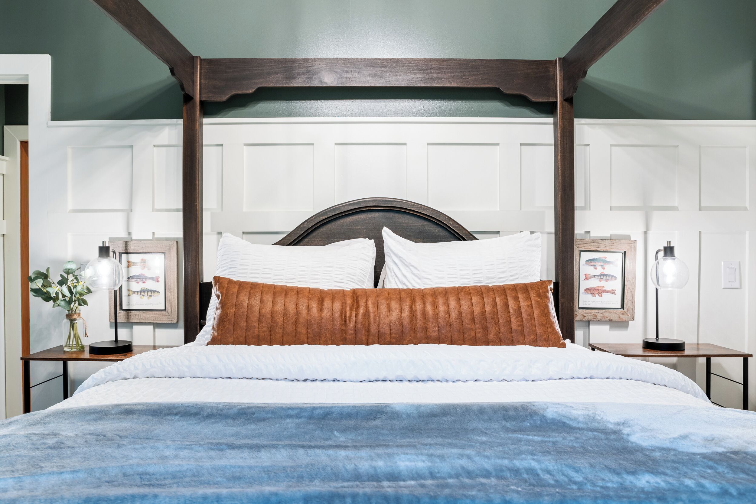 A bed with a wooden headboard, white bedding, and a blue accent.
