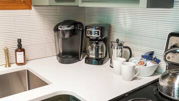 Eine Küche mit Kaffeemaschine, Wasserkocher, Kaffeekanne und Tasse.