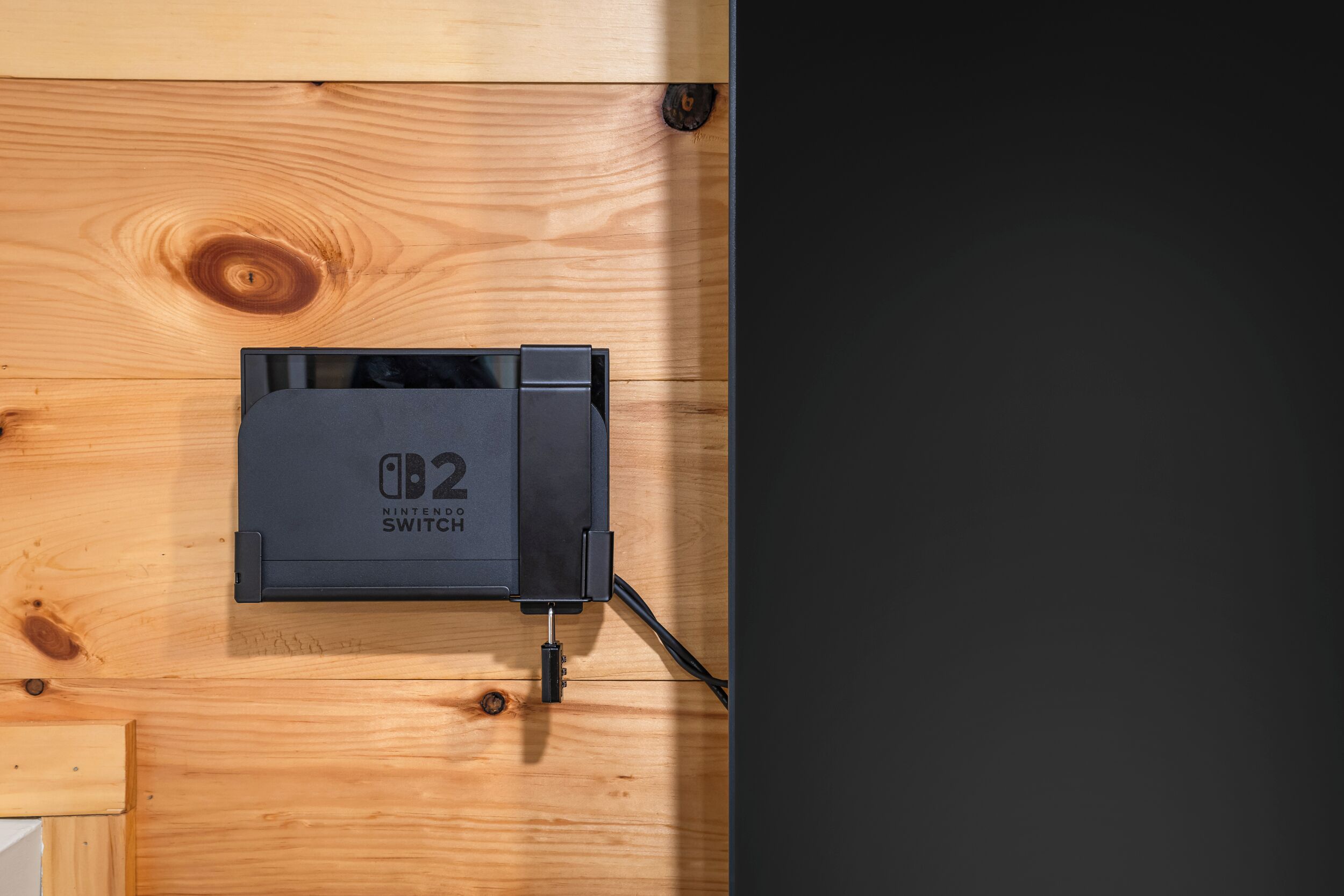 Una Nintendo Switch negra conectada a una superficie de madera.