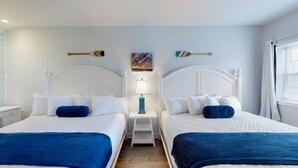 Et hotelværelse med to senge, hvide sengegavl, et natbord med lampe og et billede på væggen.