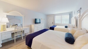 A hotel room with two beds, a desk with a chair, a television, and a wardrobe.