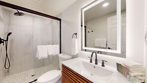 A modern bathroom with a shower, toilet, sink, and vanity. - Two-Bedroom Suite for the Ultimate Family Vacation (Cape May)