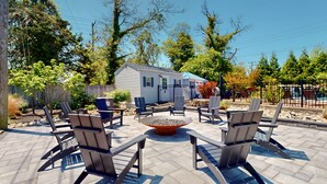 A patio area with Adirondack chairs, a fire pit, and a small shed. - Two-Bedroom Suite for the Ultimate Family Vacation (Cape May)