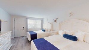 A hotel room with two beds, a TV, a dresser, and a window with curtains. - Double Queen Room for a Cozy Group Stay (Cape May)
