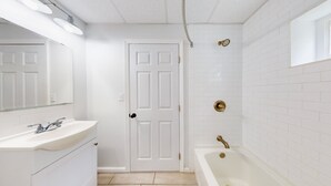 Een badkamer met een witte wastafel, spiegel en bad.