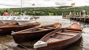 Plusieurs petites barques en bois étaient amarrées à un quai, avec en arrière-plan des collines verdoyantes et un ciel nuageux.