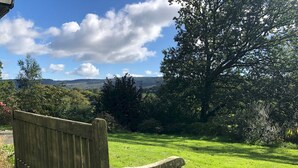 A wooden bench in a grassy area with a view of trees and hills in the background. - Beautiful Detached Farm House Near Lake Coniston - Pass the Keys (Torver)