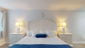 Ein Schlafzimmer mit einem großen Bett, einem weißen Kopfteil, zwei Nachttischen mit Lampen und einer Stern-Dekoration an der Wand.