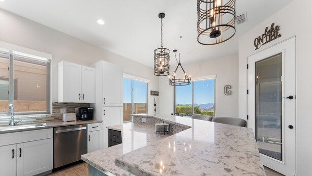 A modern kitchen with white cabinets, stainless steel appliances, and a large marble island. - Mountain Top Oasis with lake views  - WiFi included (Lake Havasu City)