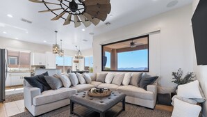 A modern living room with a sectional sofa, a coffee table, and a large window with a view. - Mountain Top Oasis with lake views  - WiFi included (Lake Havasu City)