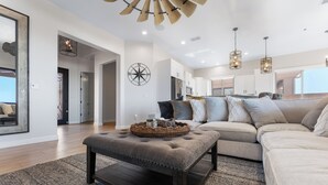 A modern living room with a sectional sofa, a dark wooden coffee table, and a large mirror. - Mountain Top Oasis with lake views  - WiFi included (Lake Havasu City)