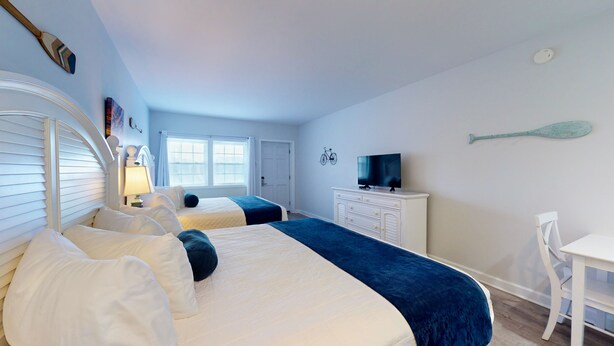 A room with two beds, a television, a desk, and a chair. - Luxury and Space in a Double King Room (Cape May)