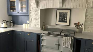 A kitchen with blue cabinets, a white stove, and a stone wall.