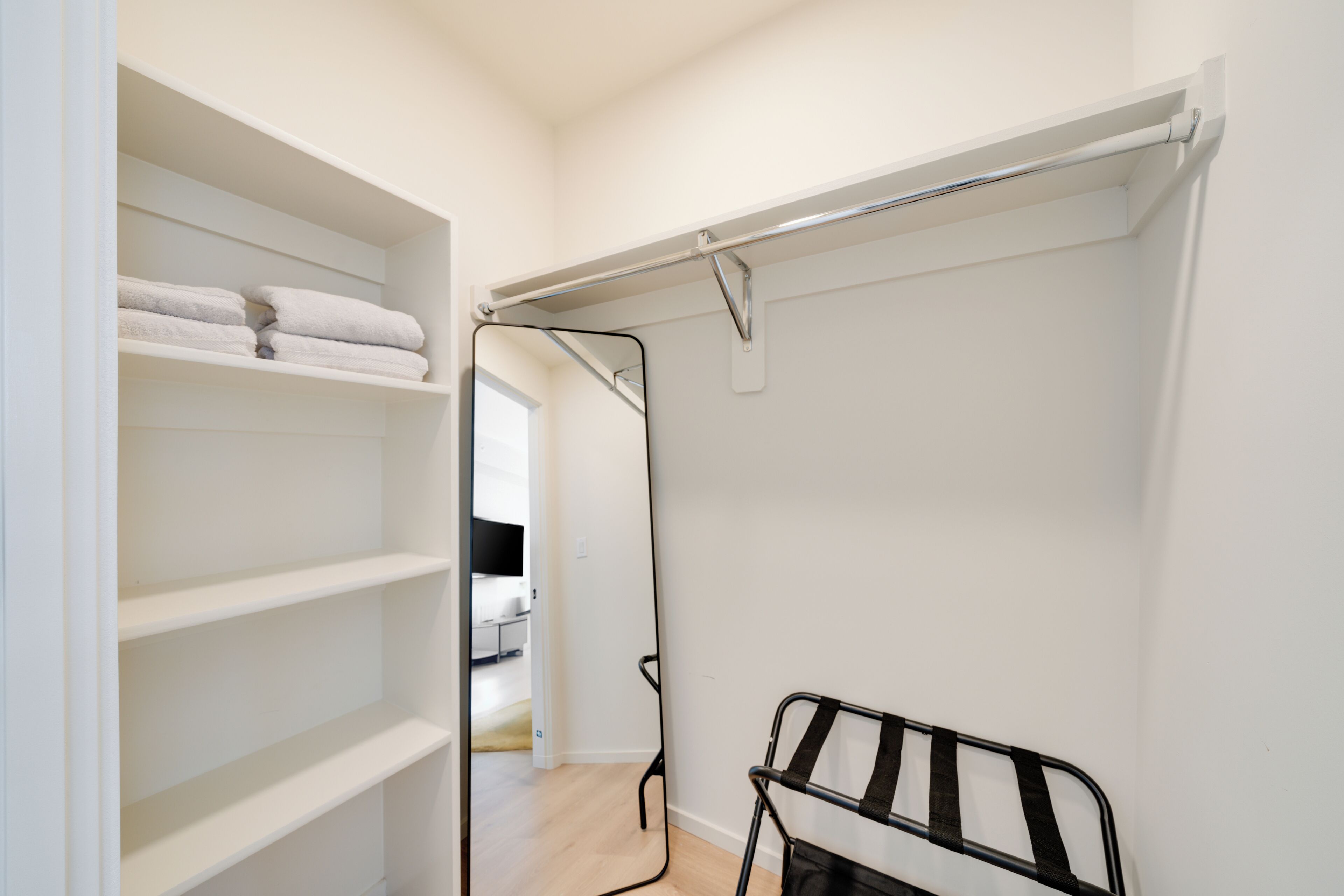 A walk-in closet with shelves and a hanging rod.