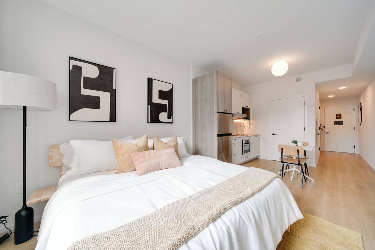 A modern bedroom with a large bed, bedside tables, a desk, and a chair.