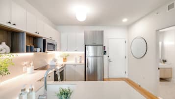A modern kitchen with white cabinets, stainless steel appliances, and a central island with a sink and plant.