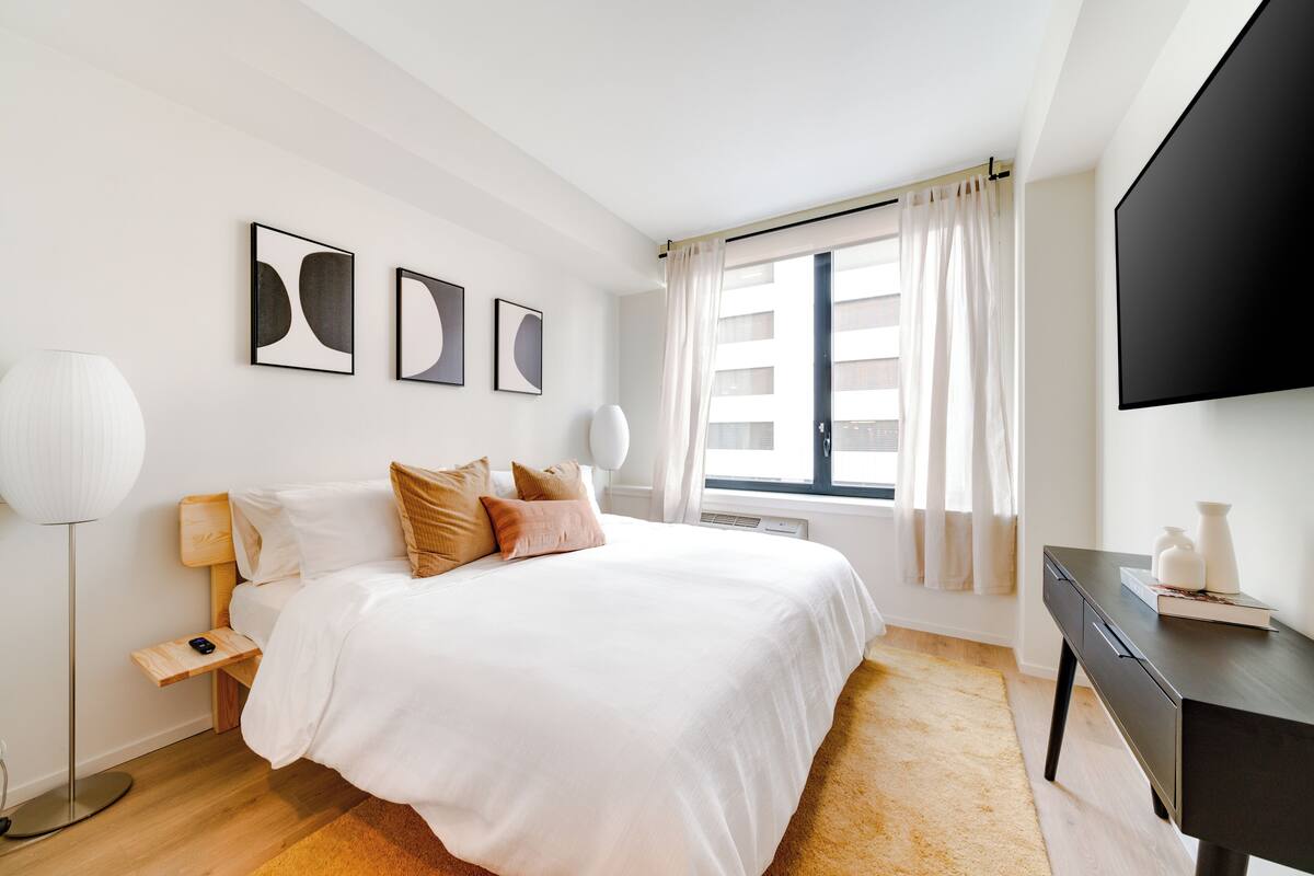 A modern hotel room with a large bed, a desk, and a flat-screen TV.