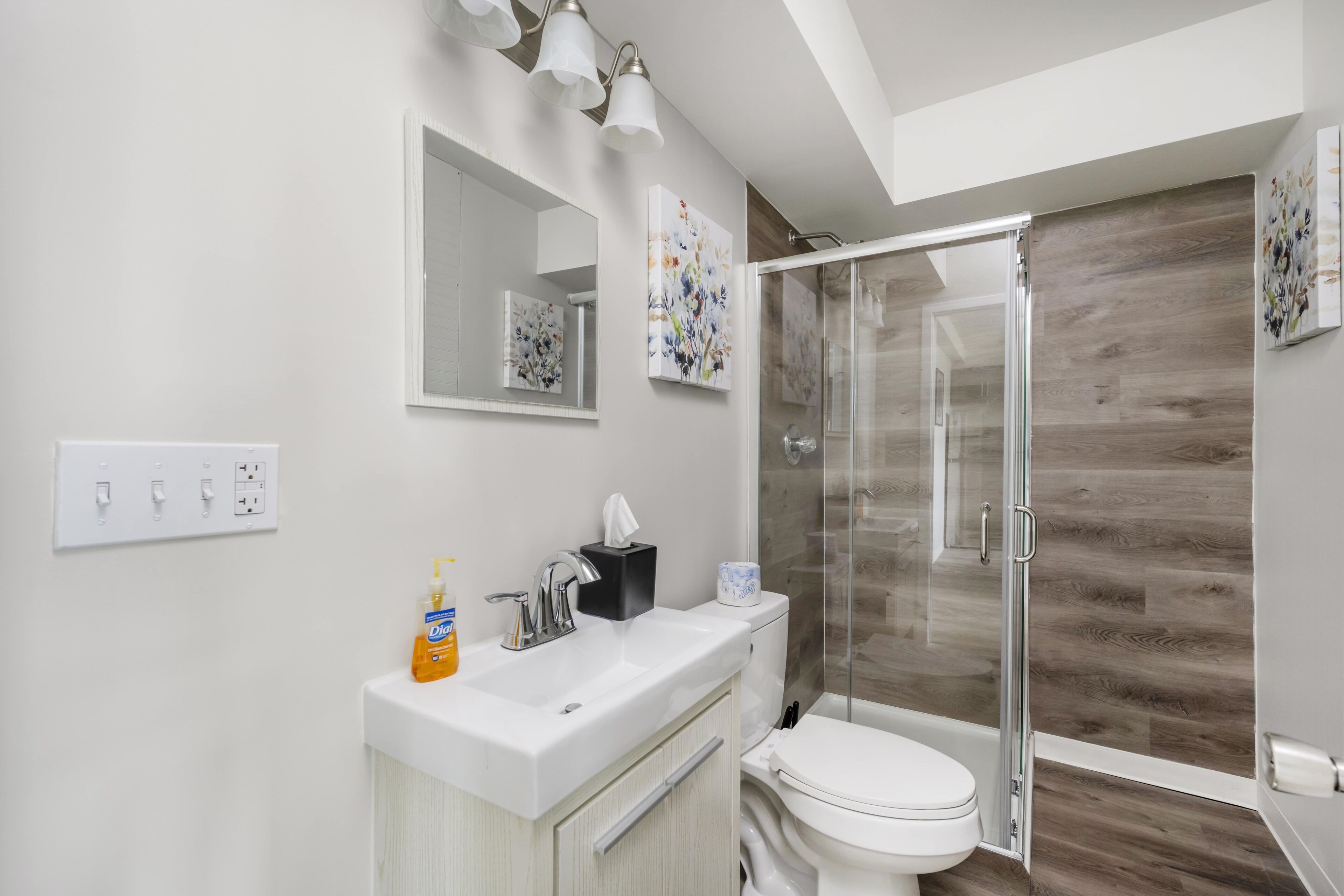 A modern bathroom with a glass shower enclosure, a white sink, and a toilet.
