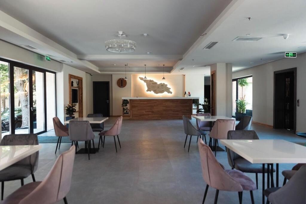 A modern hotel lobby with a reception desk, seating area, and large windows.