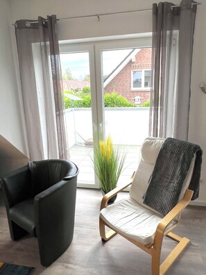 Relax in this serene space with a leather armchair, a wooden rocking chair, and a potted plant.