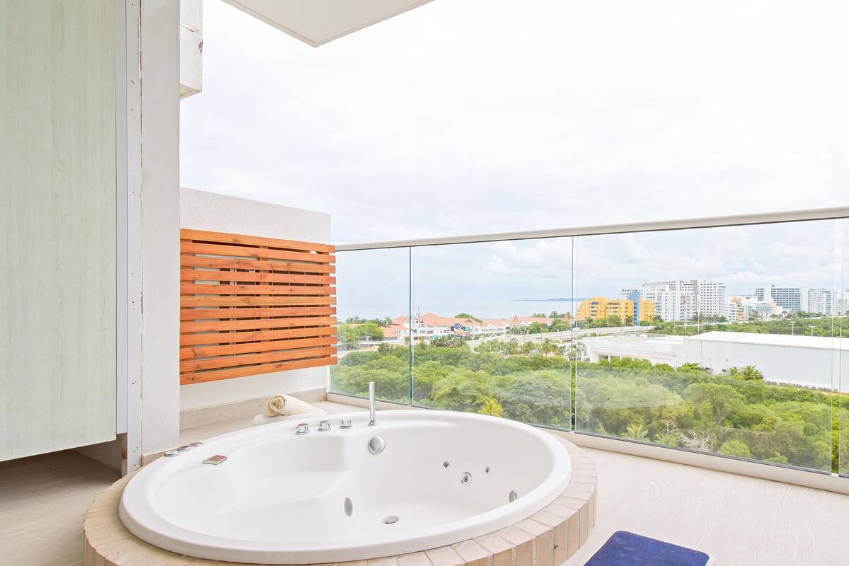 A balcony with a bathtub, a wooden slat wall, and a view of a cityscape.