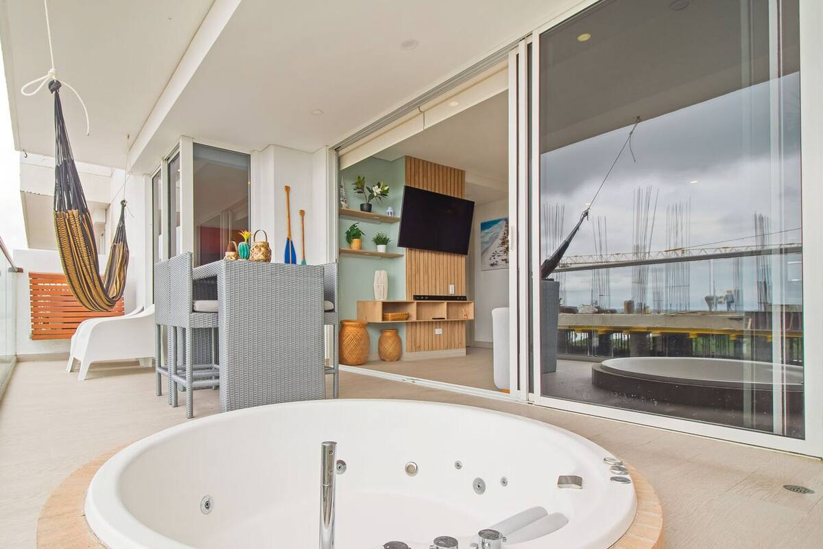 A modern interior with a large bathtub, wicker furniture, and a view of the outside.