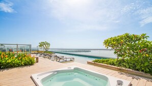 Una piscina infinita en la azotea con sillones, un jacuzzi y abundante vegetación.