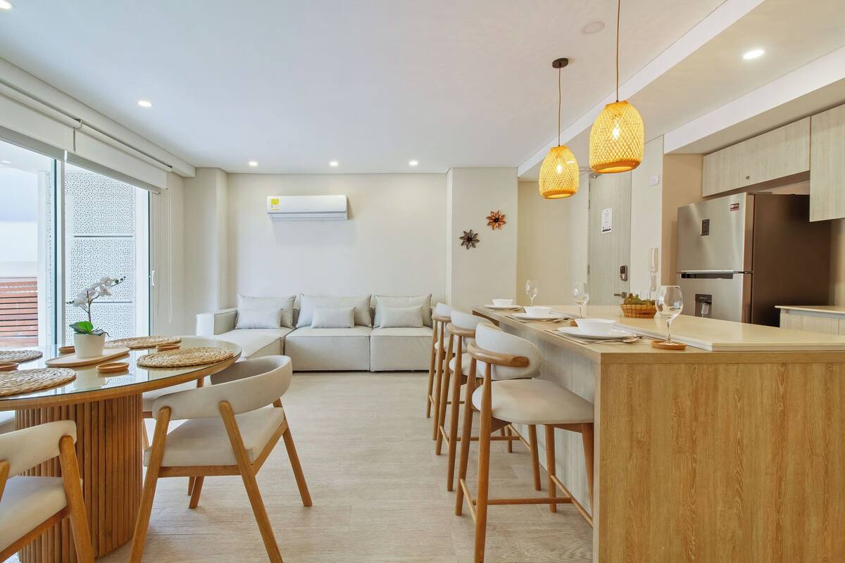 A modern kitchen with a central island, bar stools, and pendant lighting.