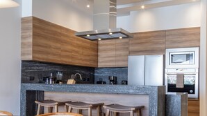 A modern kitchen with a central island, bar stools, and a dining table.