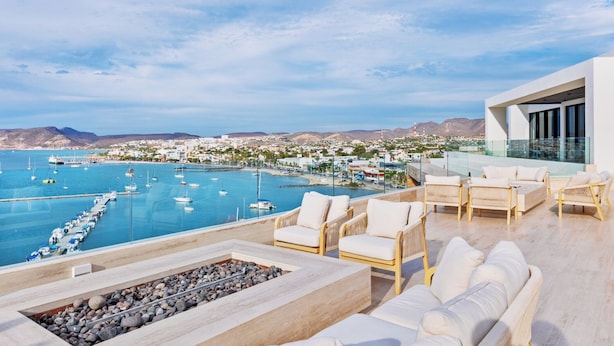 A rooftop terrace with outdoor seating, a pool, and a view of a marina and town.