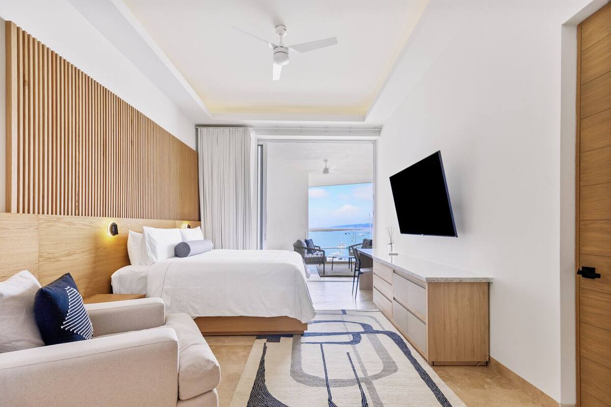 Une chambre d’hôtel moderne, dotée d’un grand lit, d’un canapé, d’un bureau et d’une télévision.