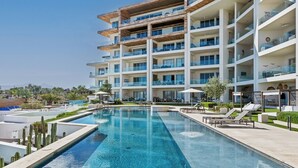 A multi-story hotel with a swimming pool, outdoor seating, and a view of the landscape.