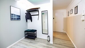 A hallway with a bench, a coat rack, a mirror, and a door.