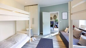 A modern, well-lit room with a bunk bed, a sofa, and a dining area.