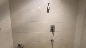 Un bagno piccolo rivestito di piastrelle, con un water, un asciugamani ad aria e un soffione della doccia.