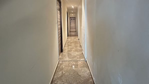 Un corridoio con pavimento in marmo, pareti bianche e porte su entrambi i lati.