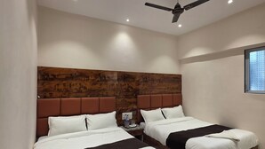 A hotel room with two beds, a wooden headboard, a ceiling fan, and a window with blinds.