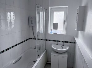 A bathroom with a bathtub, a sink, and a shower. - Art Deco 5-bedroom house with WiFi in Weston-super-Mare Close to Beach & Town (Weston-super-Mare)